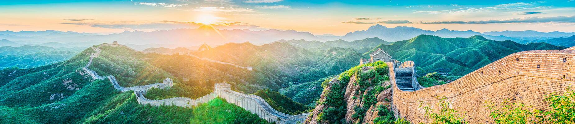 A panoramic view of the sun rising over the Great Wall of China