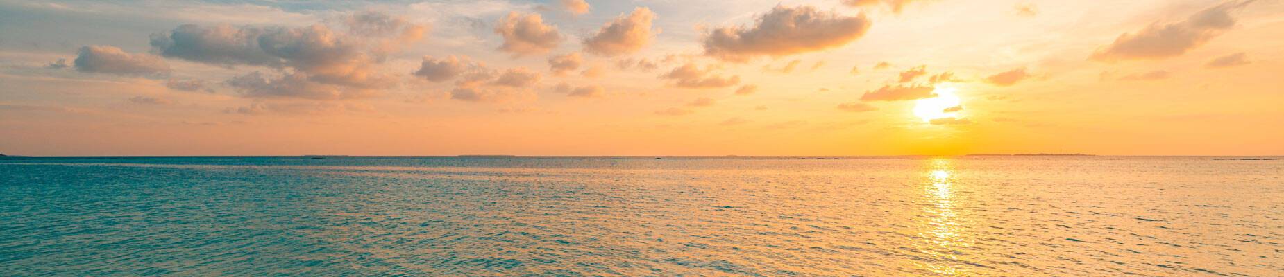 Panoramic image of the sun setting over the ocean